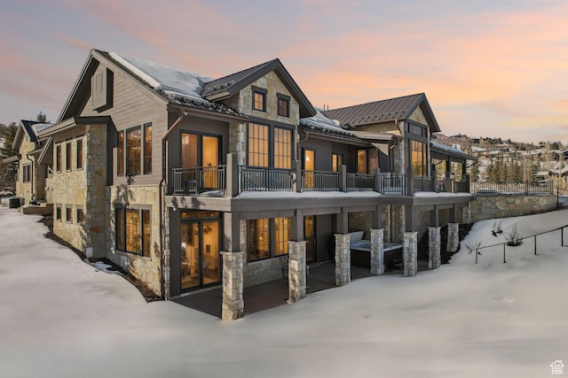 7242 Lupine Dr, Park City, UT 84098 - snow covered house with stone siding, a standing seam roof, a balcony, and metal roof