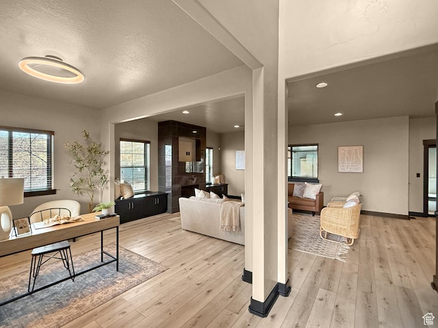 living room featuring baseboards, light wood finished floors, recessed lighting, and a textured ceiling