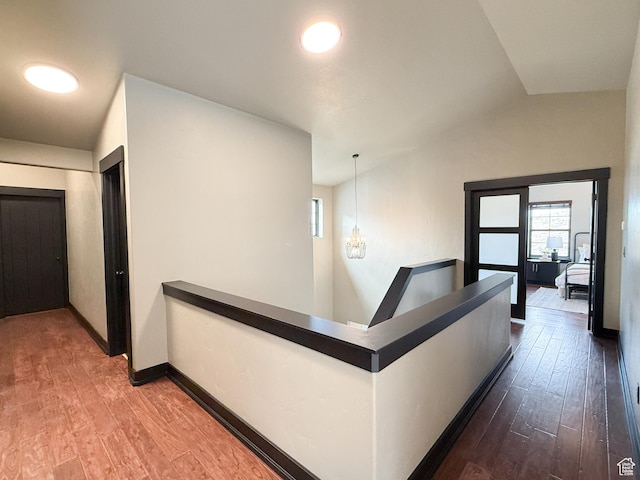 hall featuring a chandelier, baseboards, an upstairs landing, and dark wood finished floors