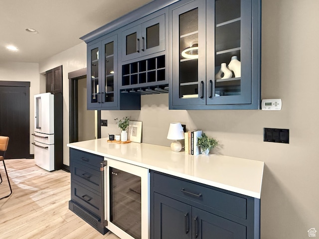 bar featuring light wood finished floors, high end fridge, recessed lighting, and beverage cooler