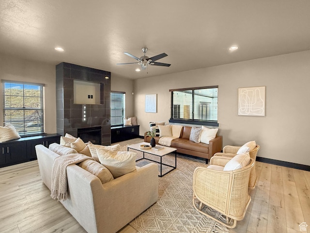 living area featuring wood finished floors, a ceiling fan, a tiled fireplace, baseboards, and recessed lighting