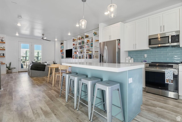 kitchen featuring pendant lighting, white cabinets, a center island, stainless steel appliances, and a kitchen breakfast bar