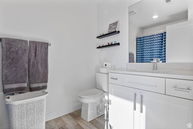 bathroom with toilet, hardwood / wood-style floors, and vanity
