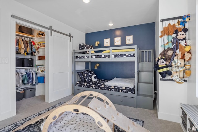 carpeted bedroom featuring a barn door and a closet