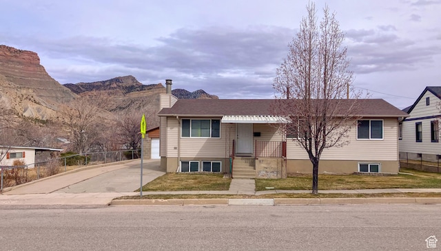 view of front of house with a chimney, fence, a mountain view, and concrete driveway