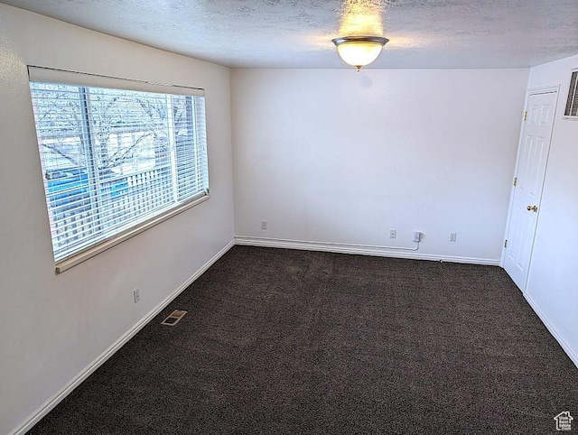 unfurnished room with dark carpet and a textured ceiling