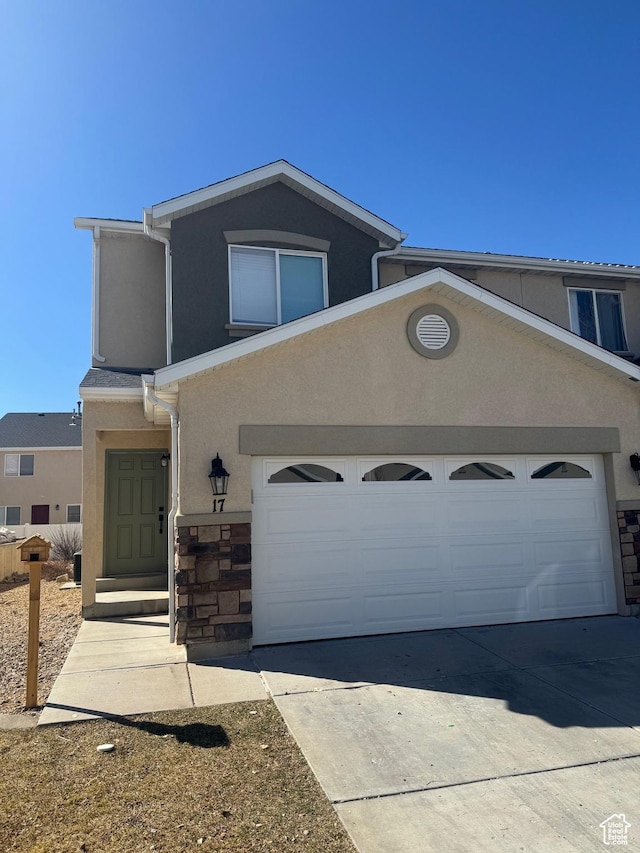 view of front of property featuring concrete driveway, a garage, stone siding, and stucco siding