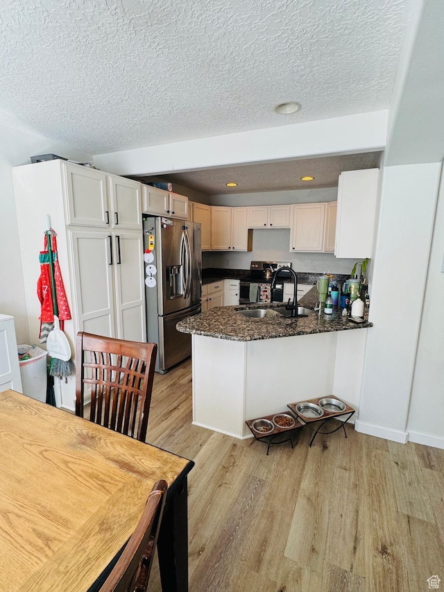 173 E Fidllers Canyon Rd Unit 17, Cedar City, UT 84721 - kitchen featuring dark stone counters, a peninsula, light wood-style floors, stainless steel appliances, and a sink