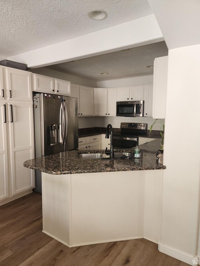 173 E Fidllers Canyon Rd Unit 17, Cedar City, UT 84721 - kitchen with stainless steel appliances, dark wood-style floors, dark stone countertops, white cabinetry, and a textured ceiling