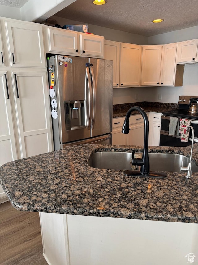 173 E Fidllers Canyon Rd Unit 17, Cedar City, UT 84721 - kitchen featuring wood finished floors, dark stone counters, a sink, stainless steel appliances, and a textured ceiling