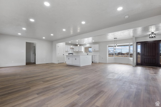 1455 E 100 S, Spanish Fork, UT 84660 - unfurnished living room with recessed lighting, baseboards, a textured ceiling, and wood finished floors