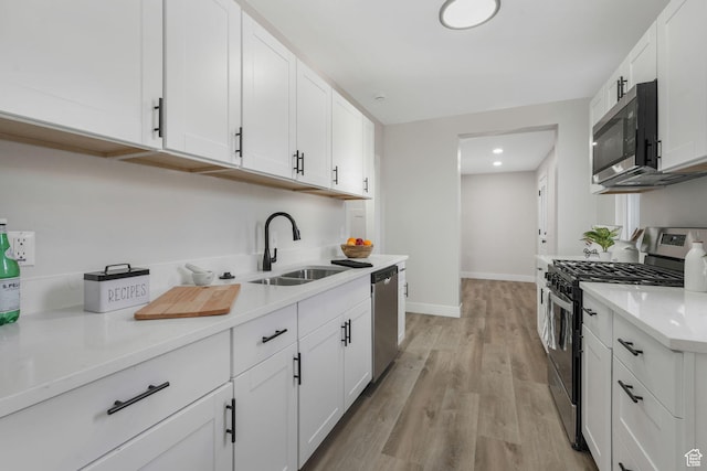 kitchen featuring stainless steel appliances, light hardwood / wood-style flooring, white cabinetry, and sink