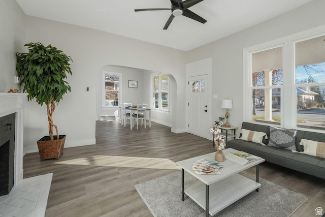 living room with ceiling fan, a fireplace, and dark hardwood / wood-style flooring