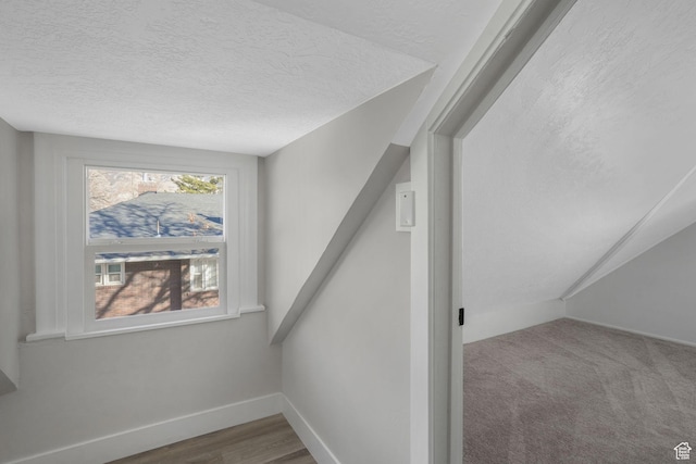 staircase with a textured ceiling and hardwood / wood-style flooring