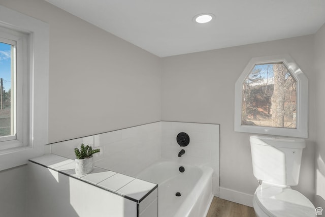 bathroom with a tub, hardwood / wood-style floors, and toilet