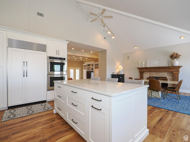 2960 E Oak Park Ln S, Holladay, UT 84117 - kitchen with high vaulted ceiling, double oven, light wood-type flooring, white cabinets, and paneled built in refrigerator