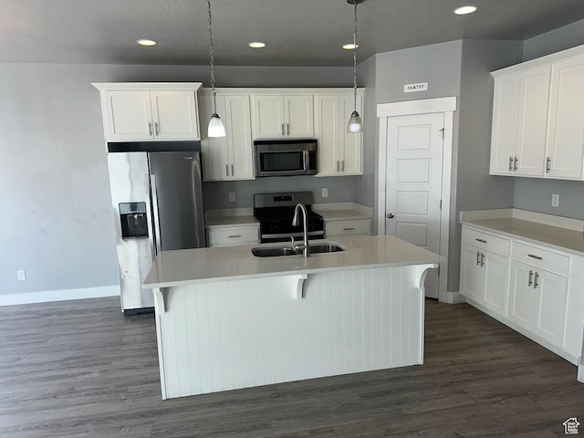 kitchen with sink, hanging light fixtures, appliances with stainless steel finishes, an island with sink, and white cabinets