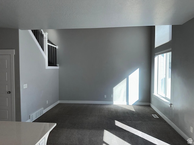 unfurnished living room featuring a textured ceiling and carpet