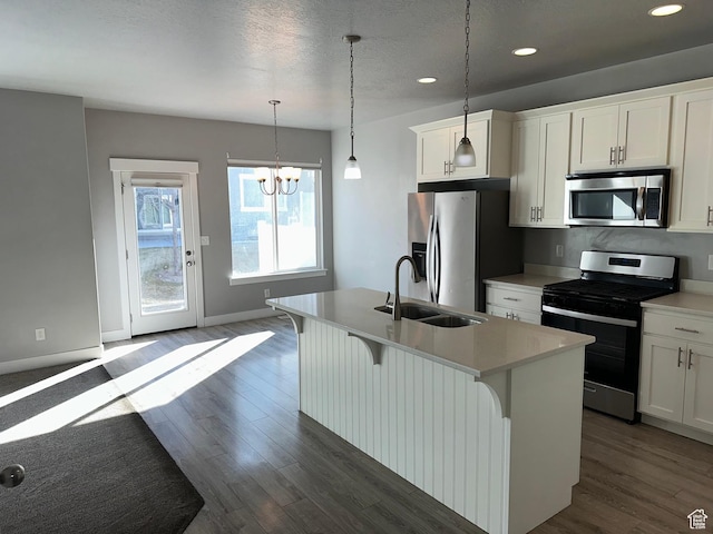 kitchen with white cabinets, sink, appliances with stainless steel finishes, and an island with sink