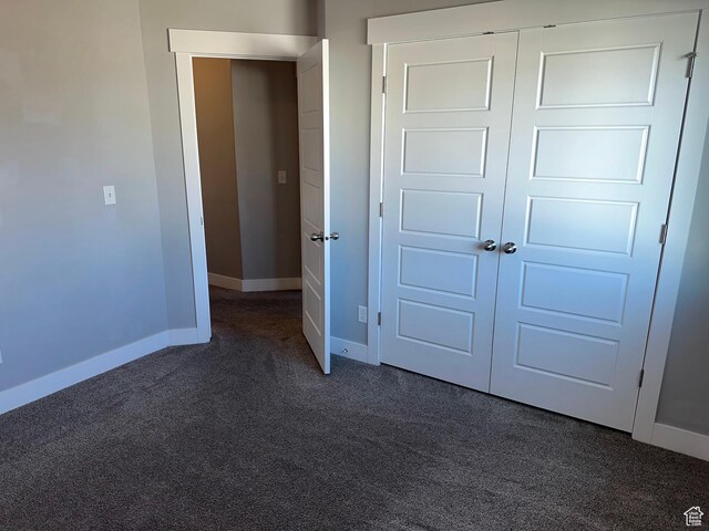 unfurnished bedroom featuring dark carpet and a closet