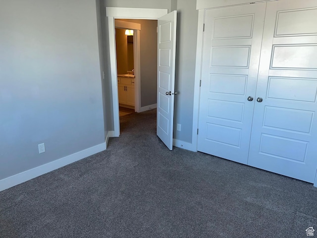 unfurnished bedroom featuring sink, dark carpet, and a closet