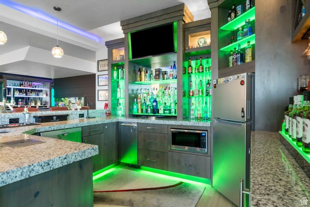 kitchen with light stone counters, sink, hanging light fixtures, and appliances with stainless steel finishes