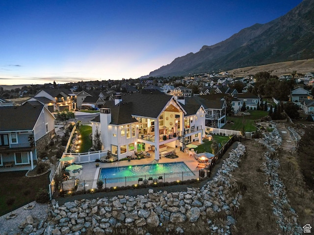 back house at dusk featuring a fenced in pool, a patio area, and a mountain view