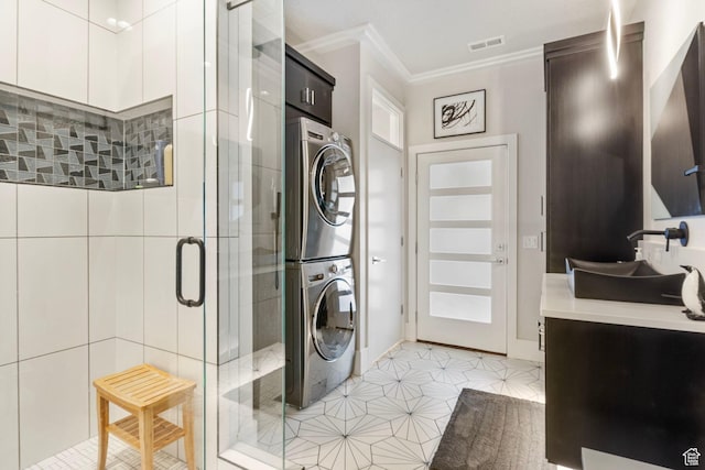laundry area featuring light tile patterned floors, crown molding, and stacked washer / dryer