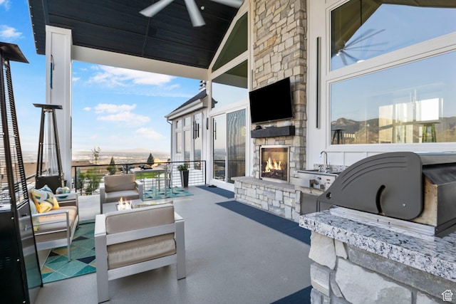 view of patio / terrace featuring ceiling fan, an outdoor kitchen, and an outdoor living space with a fireplace