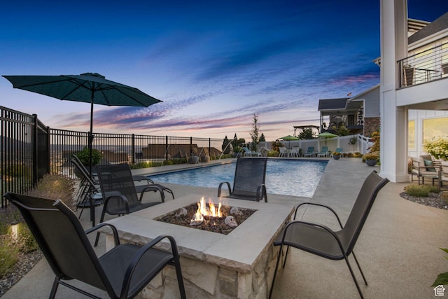 pool at dusk with a fire pit and a patio