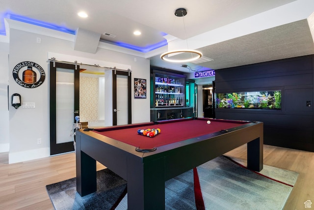 game room featuring ornamental molding, a barn door, hardwood / wood-style floors, and billiards