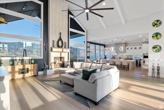 living room with high vaulted ceiling, light wood-type flooring, beamed ceiling, and a fireplace