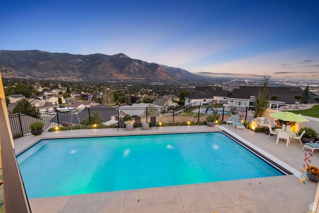 pool at dusk featuring a mountain view and a patio