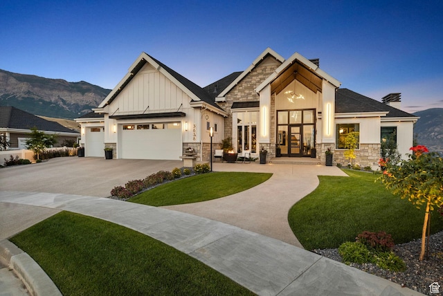 view of front of home with a garage, a mountain view, french doors, and a lawn