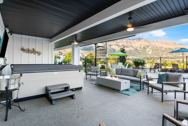 view of patio with an outdoor living space with a fire pit, a mountain view, and a hot tub