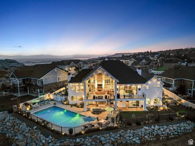 back house at dusk featuring a balcony and a patio