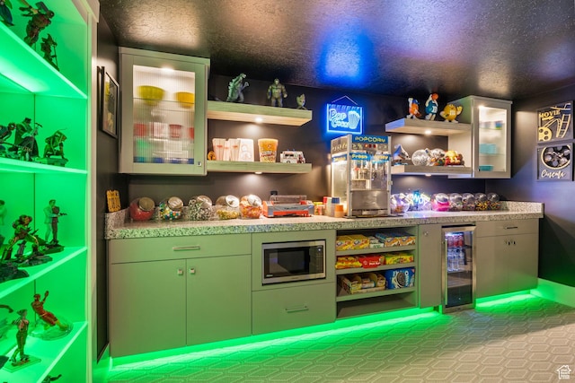 rec room with a textured ceiling, wine cooler, and bar