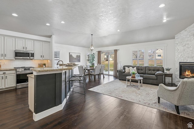6228 W Apollo Way, Highland, UT 84003 - living room with lofted ceiling, dark wood-type flooring, a stone fireplace, and a textured ceiling