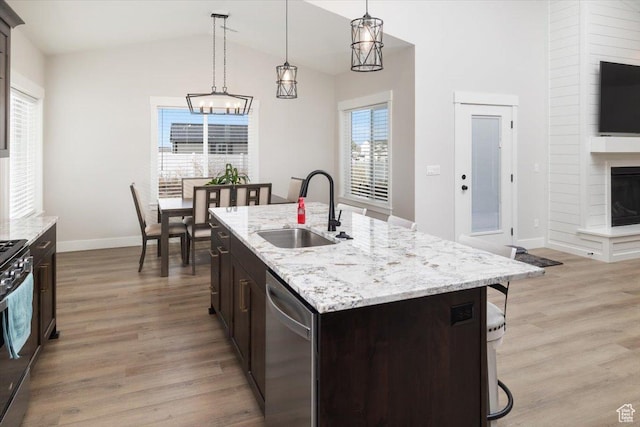 kitchen with a kitchen island with sink, dishwasher, hanging light fixtures, dark brown cabinetry, and sink