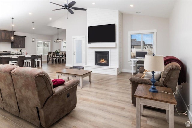 living room with a fireplace, light hardwood / wood-style floors, and ceiling fan