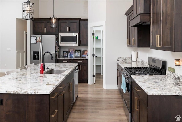 kitchen featuring dark brown cabinets, stainless steel appliances, an island with sink, and sink