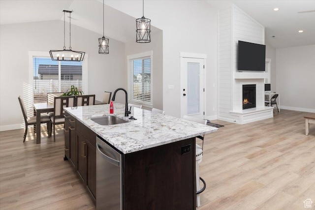 kitchen featuring dishwasher, a fireplace, pendant lighting, sink, and an island with sink