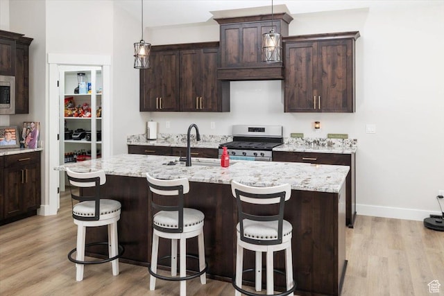 kitchen with stainless steel appliances, an island with sink, dark brown cabinetry, and sink