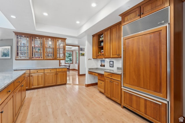 1 Spyglass Ct, Park City, UT 84060 - kitchen with paneled fridge, light stone countertops, a raised ceiling, and light hardwood / wood-style flooring