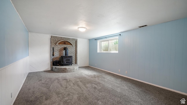 unfurnished living room with a wood stove and carpet