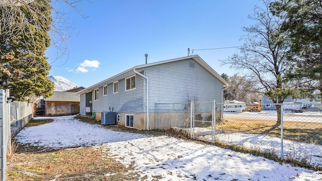 snow covered property featuring fence and cooling unit