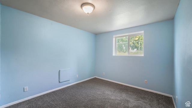 unfurnished room featuring dark colored carpet and baseboards