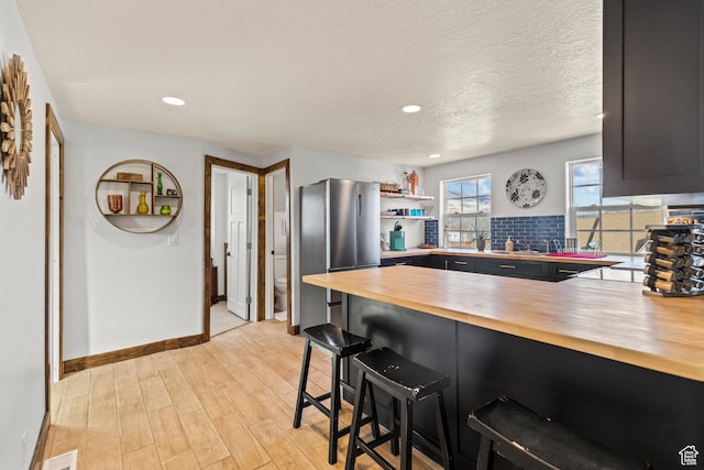 87 N 100 W, Marysvale, UT 84750 - kitchen with wooden counters, light hardwood / wood-style floors, a kitchen breakfast bar, kitchen peninsula, and stainless steel refrigerator