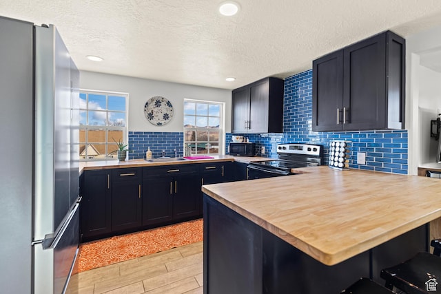 87 N 100 W, Marysvale, UT 84750 - kitchen featuring appliances with stainless steel finishes, butcher block counters, tasteful backsplash, kitchen peninsula, and a breakfast bar area