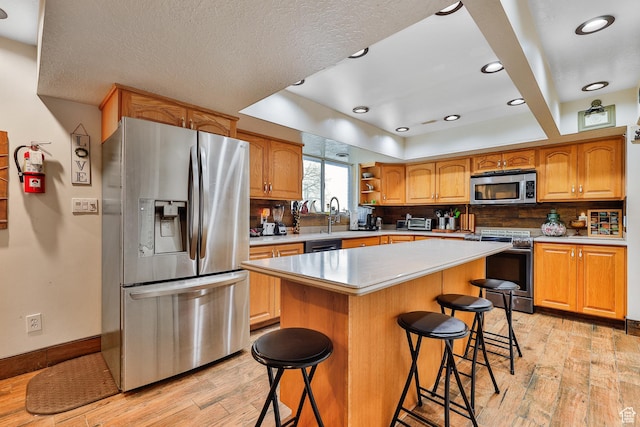1450 E Gordon Ave N, Layton, UT 84040 - kitchen with a kitchen bar, stainless steel appliances, backsplash, light wood-type flooring, and a kitchen island